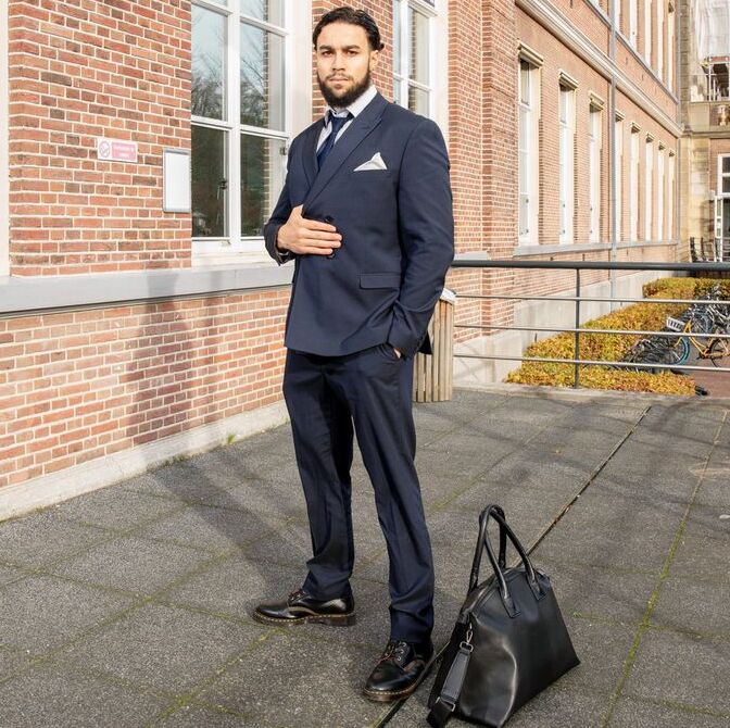Yassine Kaddouri in pak buiten voor een universiteitsgebouw.