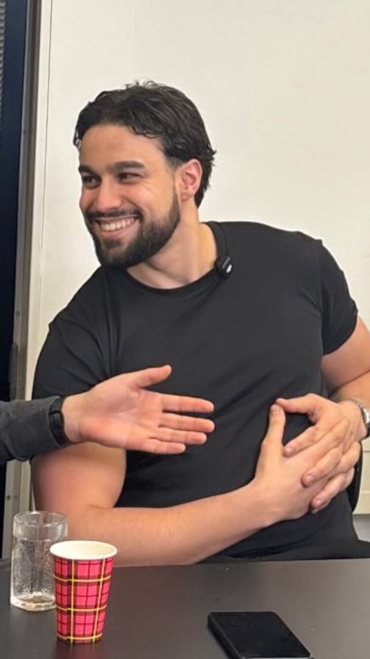 Yassine Kaddouri lachend aan tafel tijdens een opname.